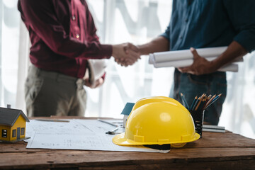 Two male engineers and a strong woman discuss blueprints and home design at a table. They work as a professional team, collaborating on construction projects with precision and expertise