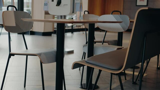 Modern cafe interior with empty tables and chairs. Stylish design with wood and metal elements. Waiting area in a coffee shop or restaurant. Minimalist furniture. Clean bright space. Cozy atmosphere.