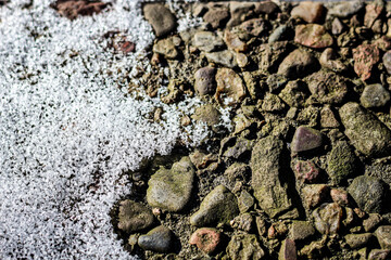 abstract close-up of snow covered rock paver rough texture brown white aggregate concrete construction grunge in winter season background