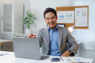 Fototapeta premium Excited asian businessman pointing at laptop in office
