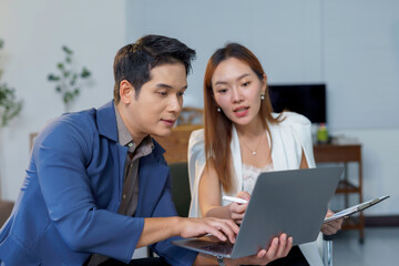 Asian businesspeople working together using laptop in modern office