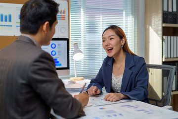 Asian businesspeople discussing and working together using computer and documents in office
