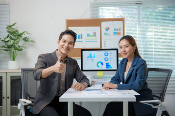Asian businesspeople showing thumbs up looking satisfied with company performance
