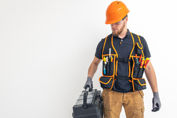 Male builder. Electrical engineer in overalls and helmet holds toolbox in hands. Space for text.