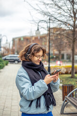 Fototapeta premium A teenage girl uses a phone in the city. Girl in the city. Technology concept.