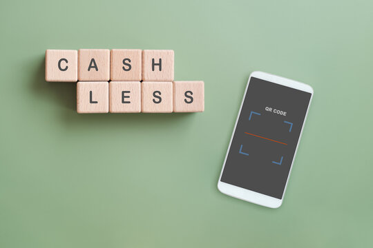 CASHLESS text on wooden cube blocks with white mobile and QR code scan on green background