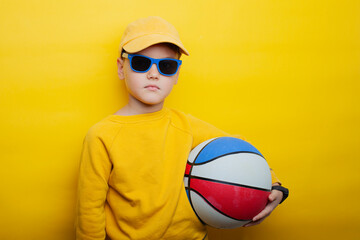 A stylish boy stands against a vibrant yellow background, dressed in a yellow sweatshirt and matching cap. 