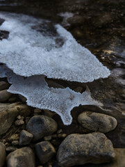 amazing forms of ice frozen between stones in winter on the river bank