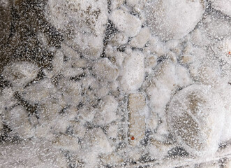 frozen river water and stones visible through the ice