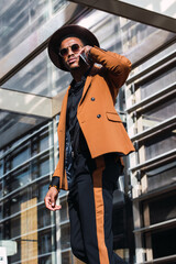 A young businessman in the city, on the move, a man in orange suit, holding a mobile phone