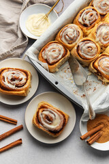 Freshly baked cinnamon rolls with cream cheese frosting and cinnamon sticks