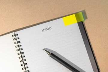 Notebook with yellow page marker note and pen on table. Blank pages for copy space. Reminder concept.