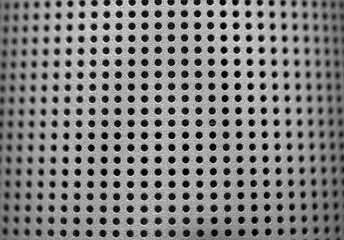 Silver speaker lattice close-up. Perforated metal texture. Modern industrial metal mesh music speaker grille.