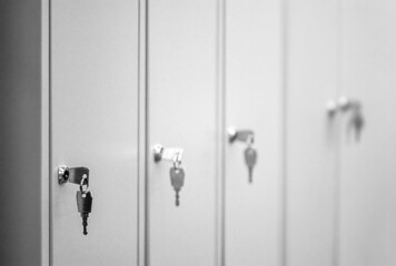 Close-up of typical grey metal school lockers with keys in the doors.