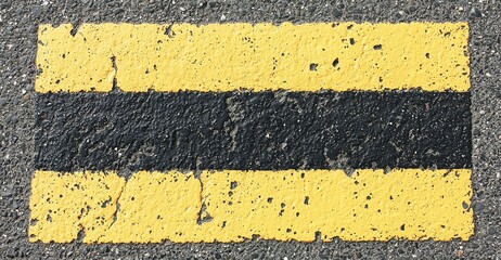 Fototapeta premium Yellow and black road markings on asphalt, indicating no parking zone