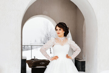 woman in a wedding dress. She stands under an arch on the street, against the backdrop of a winter...