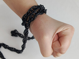 A woman's hands, clenched into a fist, are wrapped in a black chain on a white background. The concept of emotional pain, fear, and stiffness. Depression. 