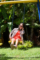 Woman with down syndrome very happy swinging on a sunny day, enjoying her vacation. Trisomy 21