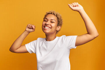 Overjoyed young black female in white mockup t-shirt encouraged with good news, celebrating...