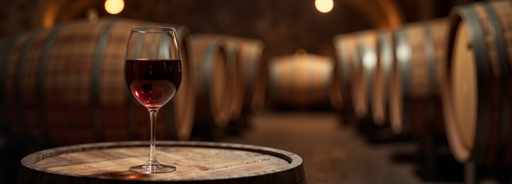 Spanish red wine glass on wooden barrel in cozy cellar, indulgence