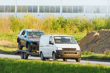 Flatbed tow truck with damaged broken cars on road