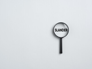 Magnifying glass showing slander word on white background