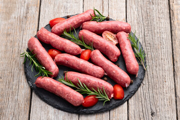 Raw beef sausages with rosemary and tomatoes photography . Top view