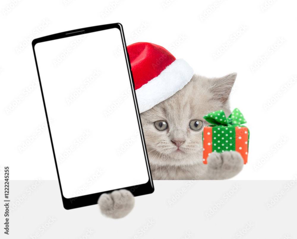 Leinwandbilder tiny kitten wearing red christmas hat holds tiny gift box and smartphone with white blank screen in 