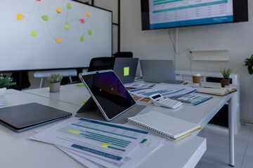 Laptop Computer, notebook, and eyeglasses sitting on a desk in a large open plan office space after working hours	