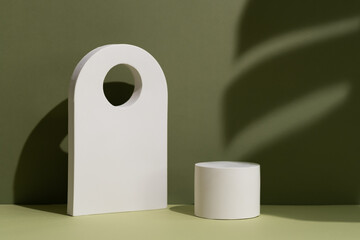Geometric white scene with the shadow of a monstera leaf on a green background. A premium podium for advertising and presentation of your product. Showcase, display case.