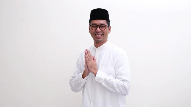 A muslim man smiling happy doing greeting pose with hand praying gesture