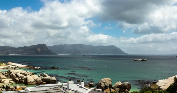 A static Time Lapse captured from the coast with a helicopter drill being performed in the foreground, fast-moving cloud cover and mountains in the background.