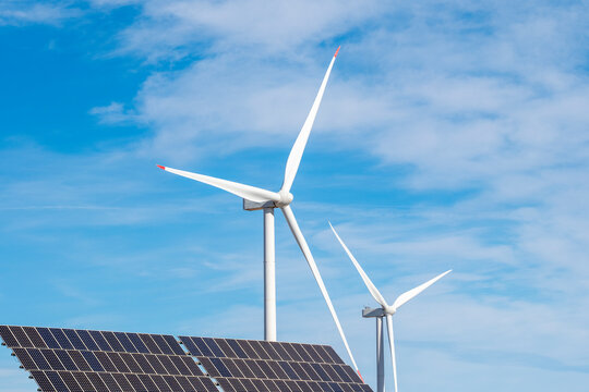 A vibrant setup showcasing wind turbines adjacent to solar panels under a clear blue sky, highlighting the synergy between two renewable energy sources in Zaragoza Spain
