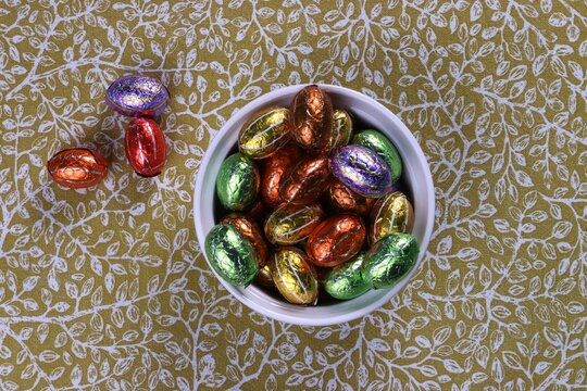 Chocolate Easter eggs in foil in a white bowl, a treat for the Easter holidays.