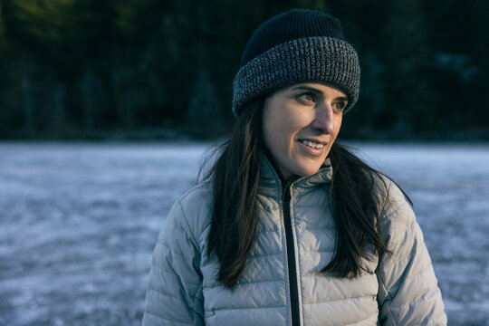 Portrait of woman in winter gear on an icy lake with a forest backdrop