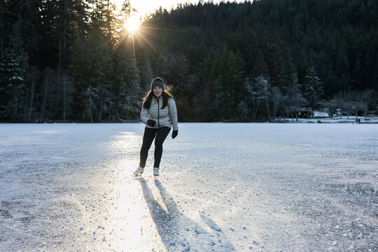 Ice skater gliding on a reflective frozen lake at sunset