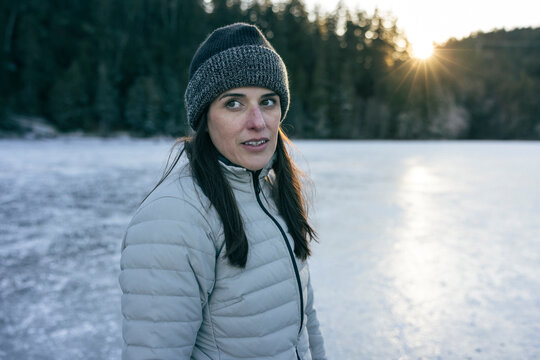 Close-up of a woman ice skating on an icy lake with a forest backdrop