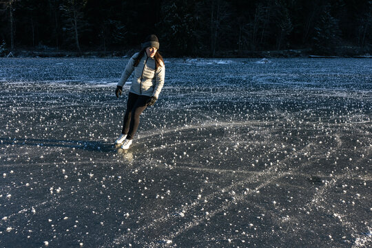 Winter scene of a ice skater enjoying the outdoors on a frozen lake.