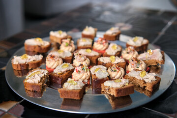 A platter of lobster toasts, featuring small pieces of bread topped with creamy lobster spread, garnished with herbs and lemon zest, arranged appealingly.