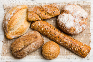 Assortment of freshly baked bread with napkin on rustic table top view. Healthy unleavened bread. French bread