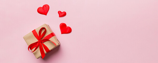 Valentine day composition: red gift box with bow and heart. Christmas present. View from above. Space for text. Holday greeting card