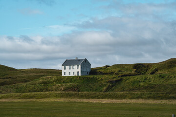 A serene mountain landscape featuring a traditional Icelandic house along the famous Ring Road (Route 1) near Vik in South Iceland, blending nature and culture