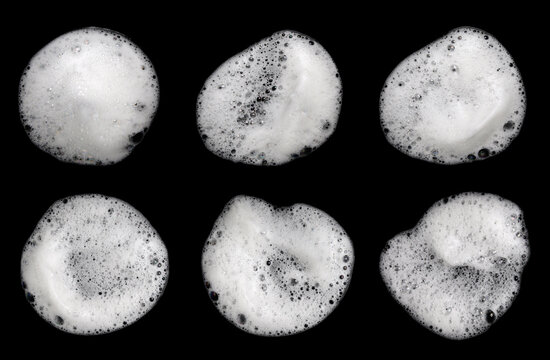 Liquid white foam from soap, shampoo or bath foam. Abstract soap bubbles. Set of soap bubbles. Separated soap bubbles on black background with contrasting texture.
