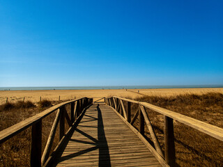 View of the wooden walkway leading to the beach on a sunny summer day.
