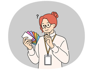 Fototapeta premium Woman designer holds palette of cards of different colors, choosing desired shade to use in design. Business girl working as designer makes decision on choosing main color for corporate identity