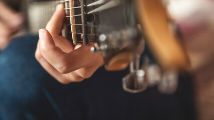Close-up of a women playing a guitar on a bed. Guitar strings visible. Relaxed atmosphere with an...