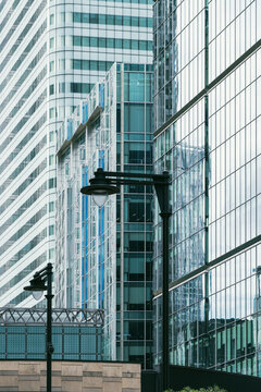 A stunning view of modern glass buildings, showcasing their reflective surfaces and unique design, contrasted with sleek street lamps at the forefront of the scene.
