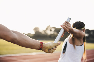 Close-up of a athlete passing the baton to a female athlete