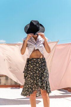 Fashionable young woman wearing hat, wrap-around blouse and skirt with floral design