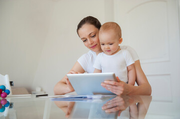 Mother and little daughter using tablet together at home